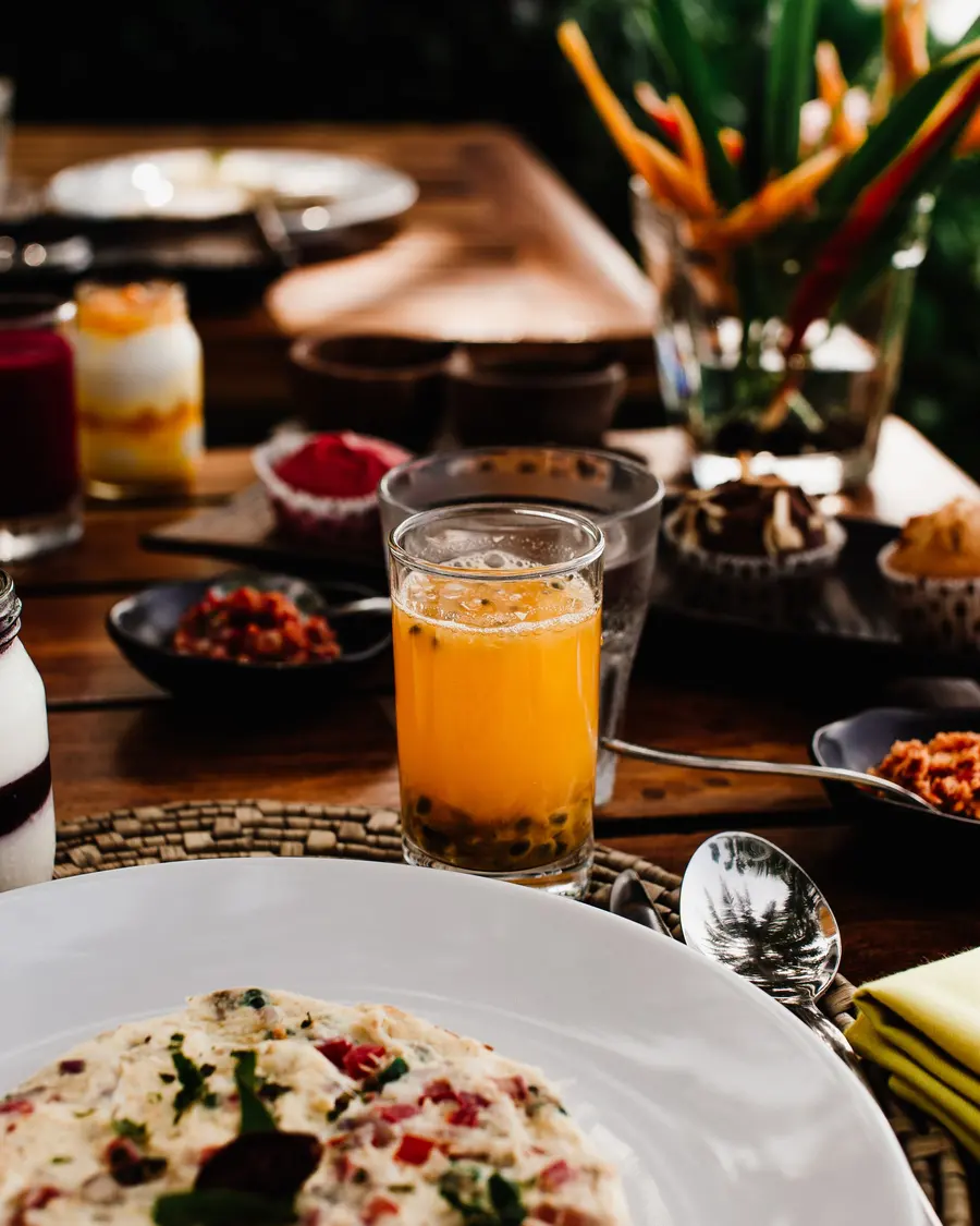 Mesa de café da manhã com suco de laranja, granola e frutas