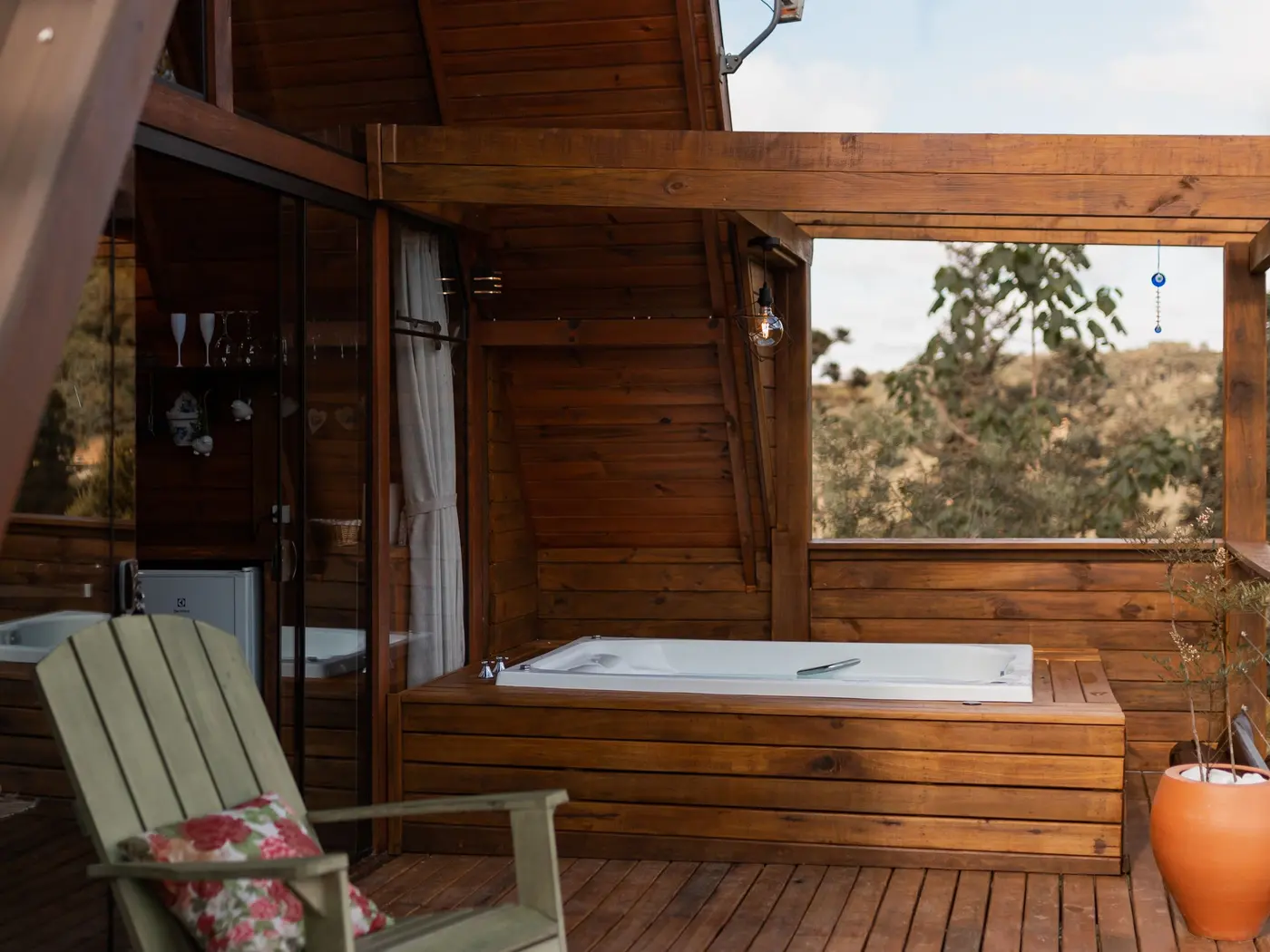 Deck de madeira com ofurô, cadeiras de varanda e vista para o céu