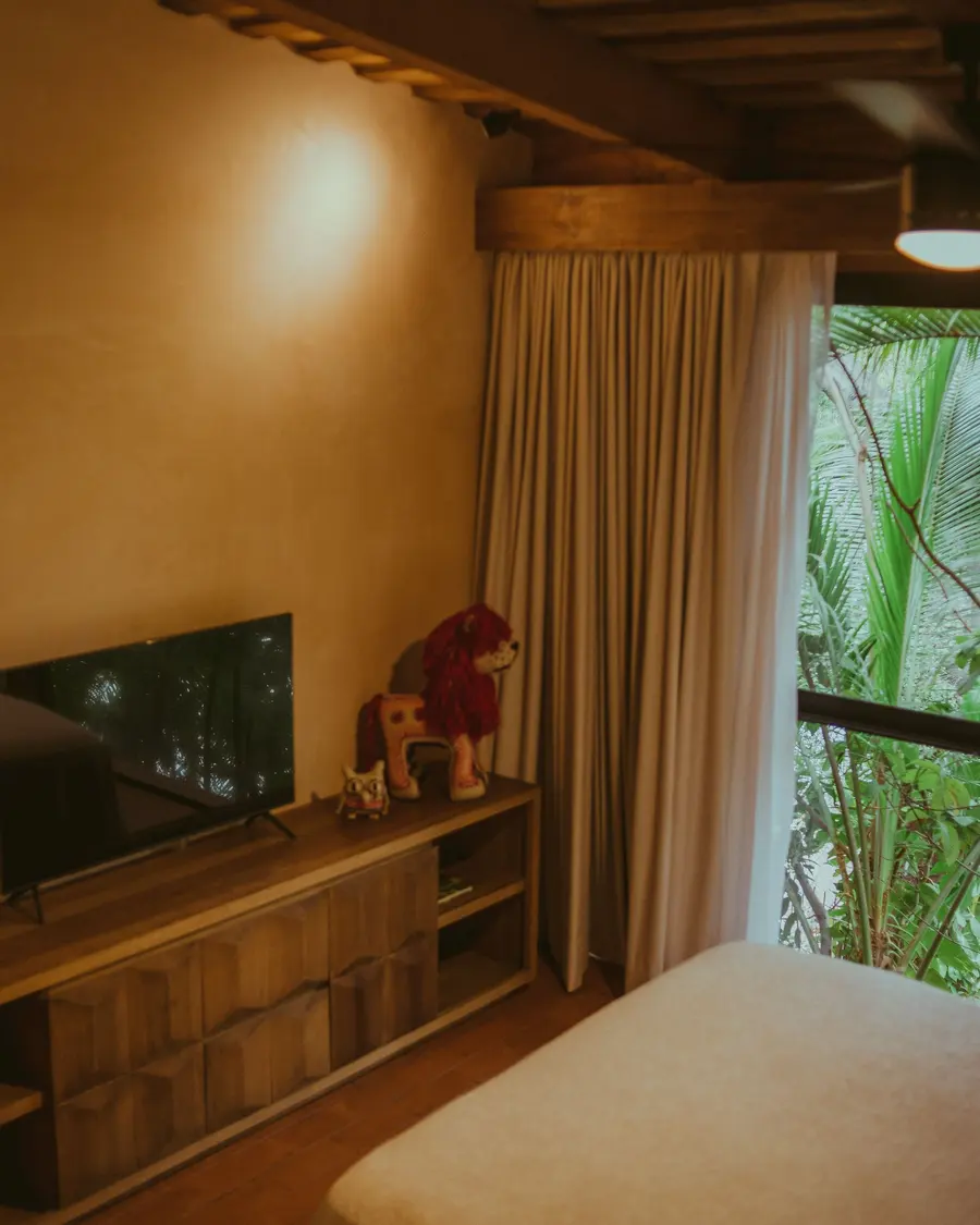 Canto do quarto com móvel de madeira e cortina de linho